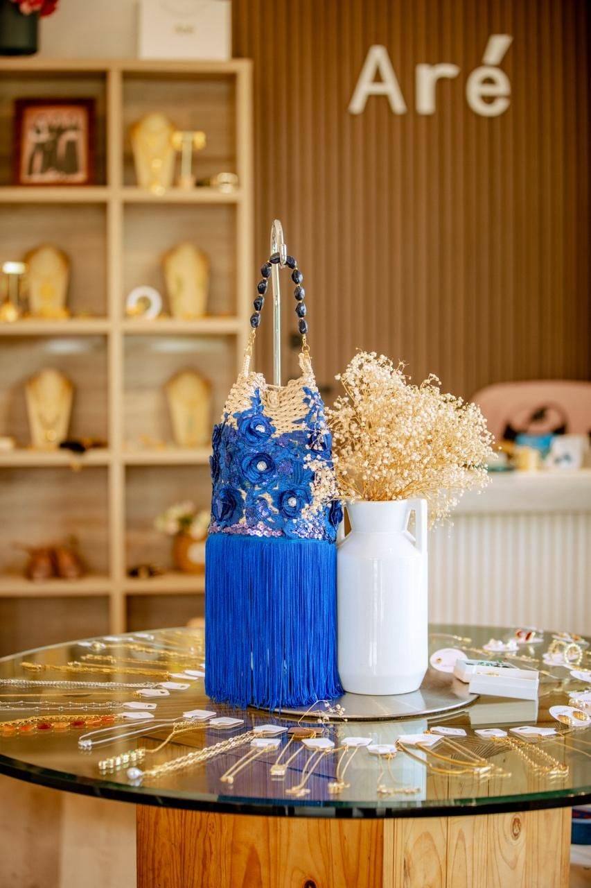 Cartera azul con flecos sobre una mesa de la tienda Aré