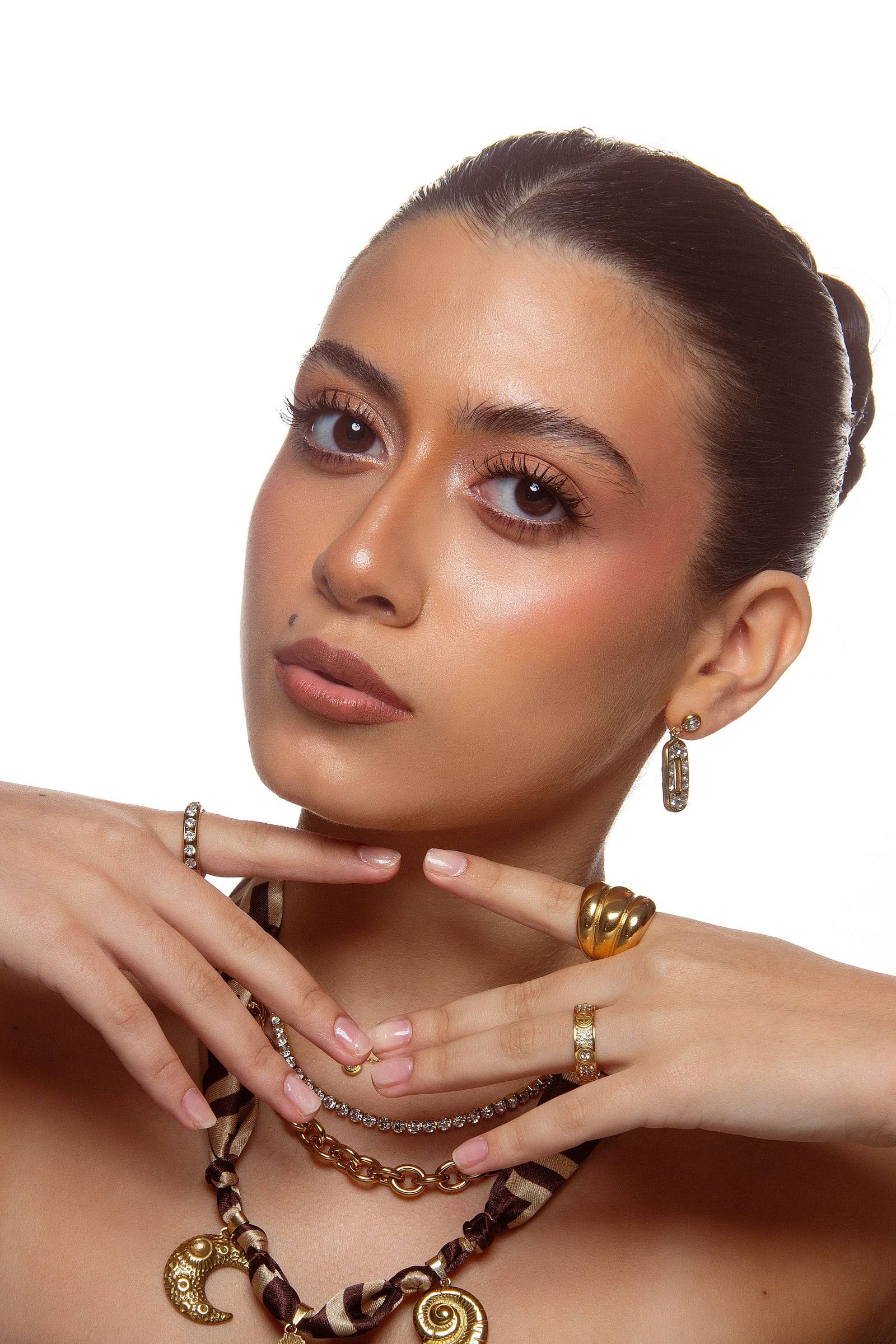 Modelo con anillos dorados de Aré, las manos junto al rostro